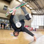 Skateboarder performing invert/handplant on skate ramp