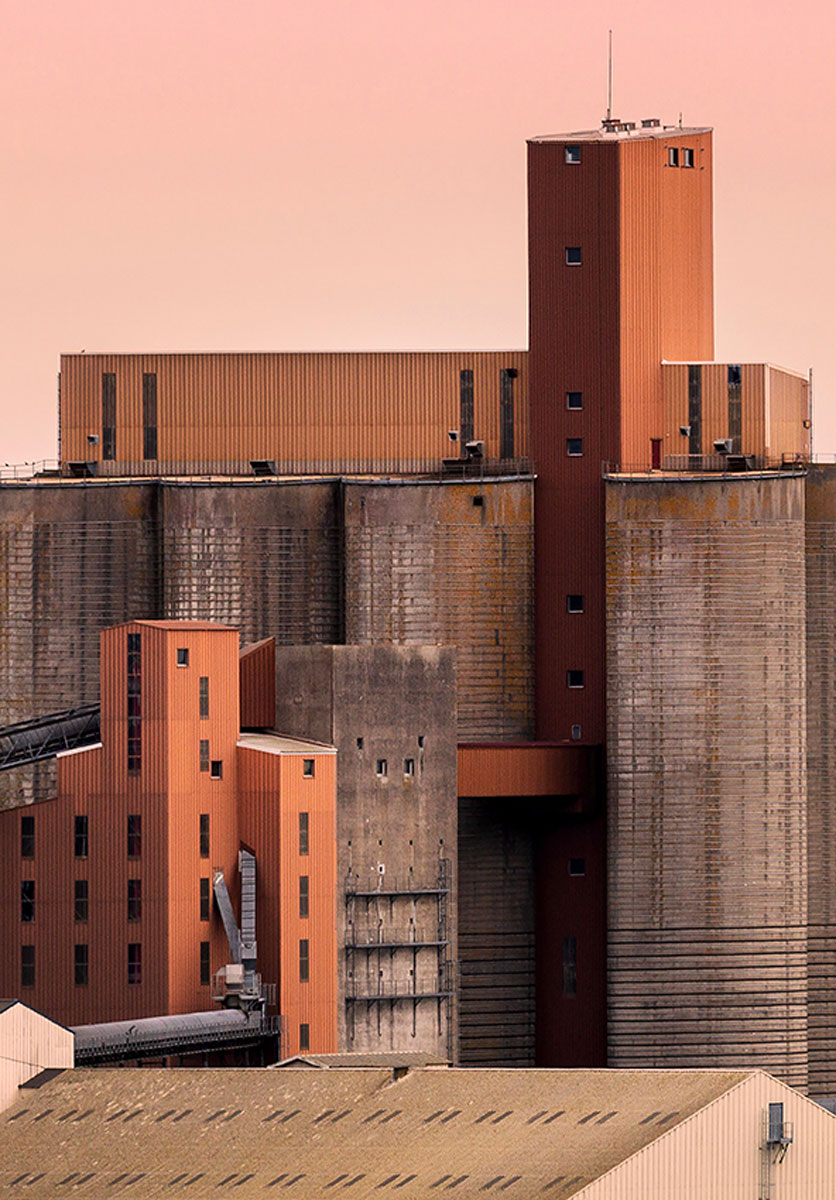The Silos, a collage-like image of silos and surrounding buildings in eye-catching rosy hues at the Port of Brest in France. © Mark Benham, United Kingdom, Winner, Open Competition, Architecture, Sony World Photography Awards 2023