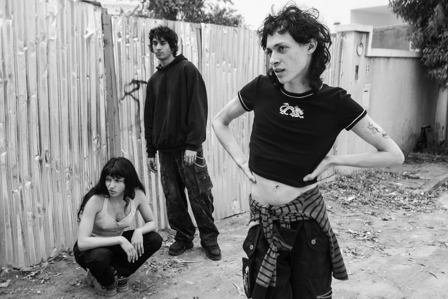 Three young people in a suburban setting display distinct punk-influenced fashion, with an air of nonconformity and casual defiance.